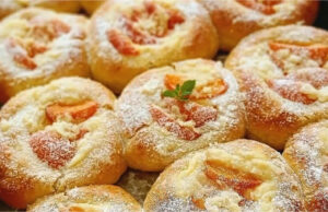 Moist Yeast Buns with Vanilla Pudding, Apricots, and Rum Butter A baking tray full of golden round yeast buns with pudding, bright orange apricots, and crunchy streusel, with glossy brushed edges.