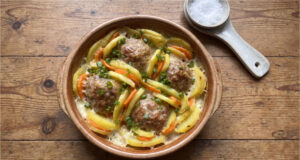 Baked Potatoes with Meatballs: Hearty Family Meal with Béchamel and Cheese Baked potatoes with meatballs, carrots, béchamel and cheese in a baking dish