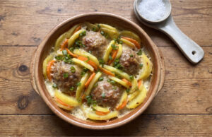 Baked Potatoes with Meatballs: Hearty Family Meal with Béchamel and Cheese Baked potatoes with meatballs, carrots, béchamel and cheese in a baking dish