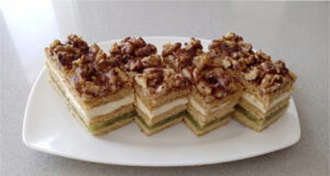 Honey Cake Slices with Apples: Three Honey Layers, Delicate Cream, and Refreshing Fruit Filling Honey cake slices with apples on a tray topped with chocolate glaze