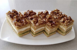 Honey Cake Slices with Apples: Three Honey Layers, Delicate Cream, and Refreshing Fruit Filling Honey cake slices with apples on a tray topped with chocolate glaze
