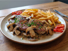 Pork Shoulder with Mushrooms: Juicy Meat with Creamy Sauce and Homemade Fries Pork shoulder with mushrooms, creamy sauce and homemade fries on a plate