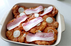 Reverse Schnitzels from Pork or Chicken: Crispy, Juicy, and Oven-Baked Reverse schnitzels with bacon and onion on a tray